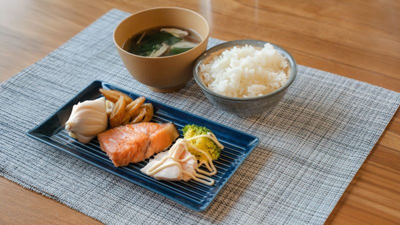 焼き鮭と納豆、ご飯、味噌汁、野菜を組み合わせた和食の献立